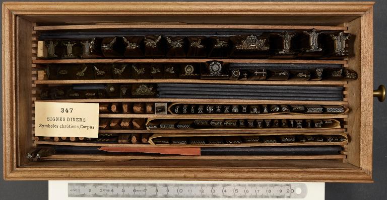 Boîte de poinçons typographiques : ornement symbole chrétien, corpus et croisillon